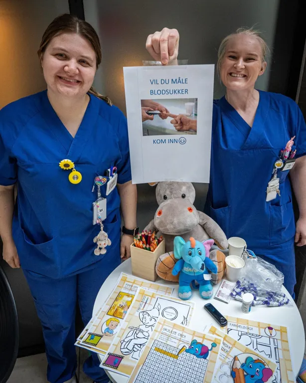 Kvinner som står ved siden av et bord med en bamse og et skilt