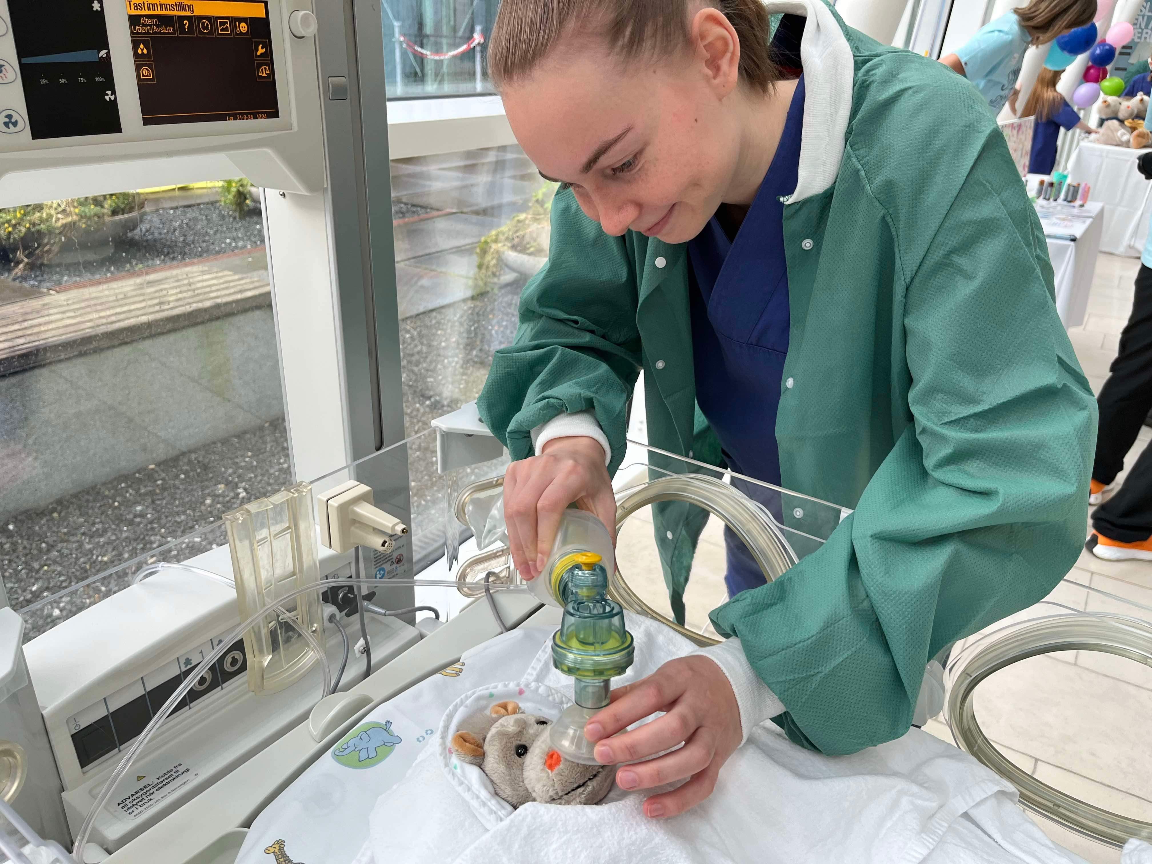 En person i laboratoriefrakk som ser på et lite dyr i et rør