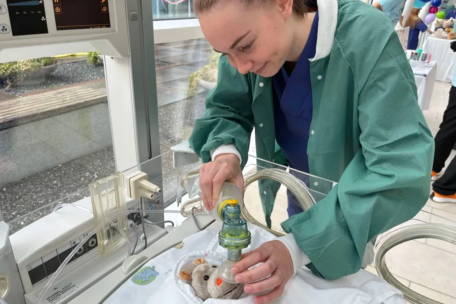 En person i laboratoriefrakk som ser på et lite dyr i et rør