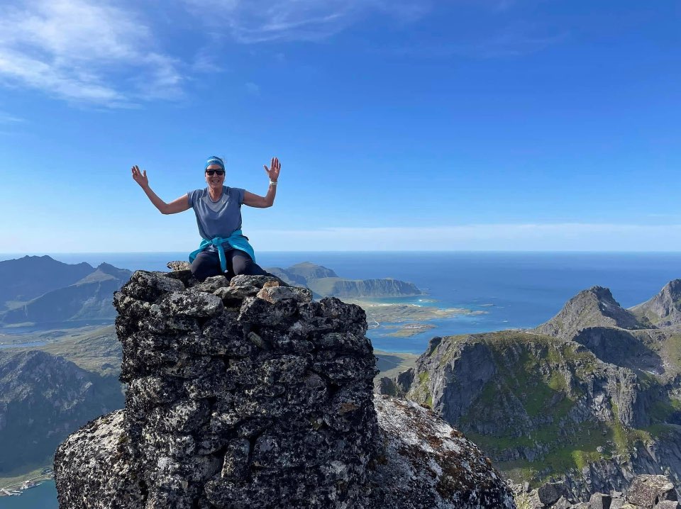 Dame med henda i været på en fjelltopp