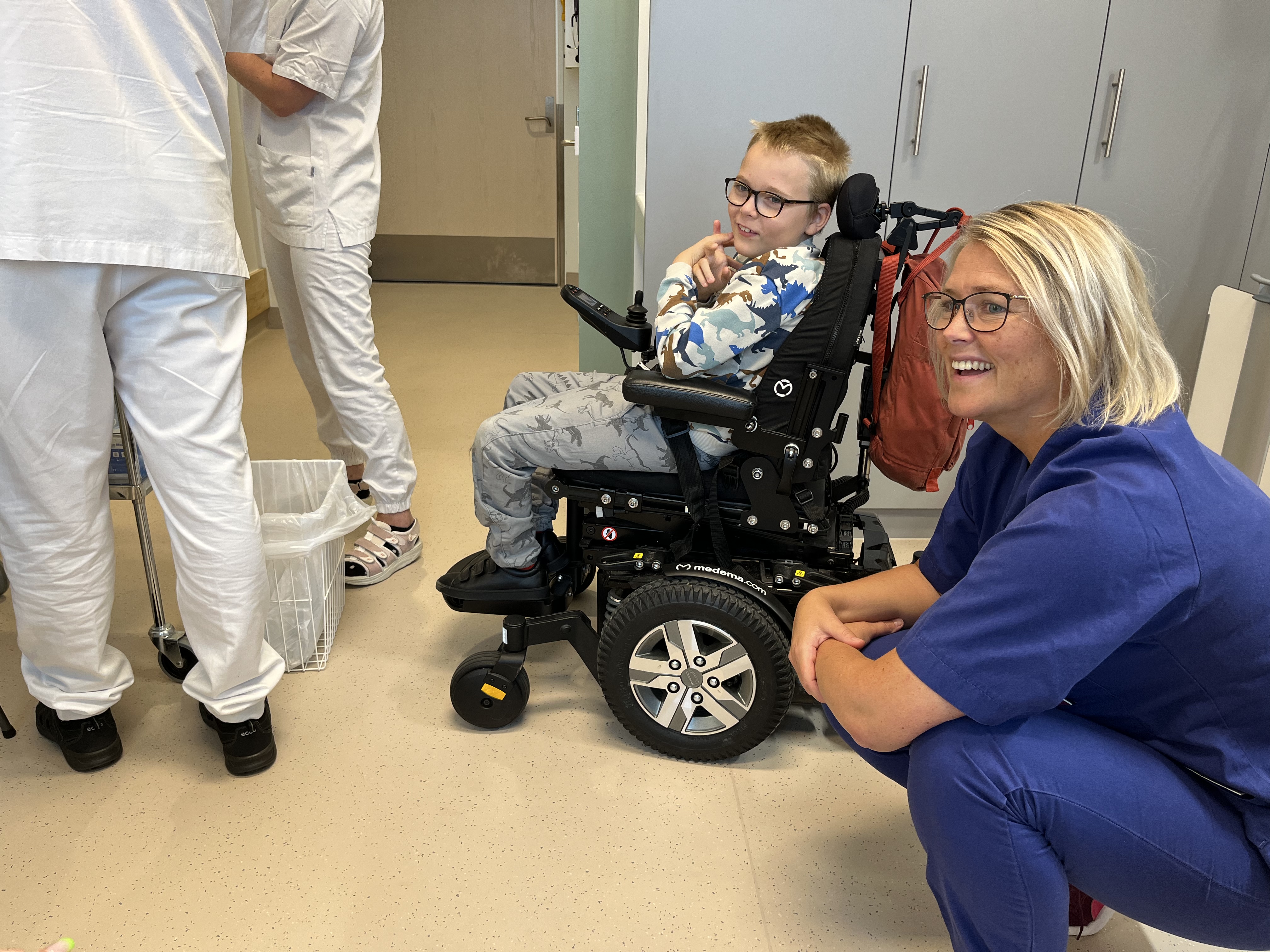 sykepleier og gutt i rullestol sammen