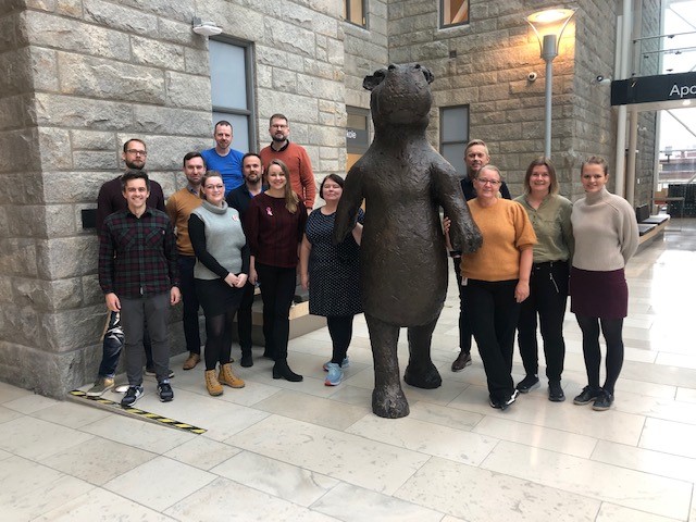 Gruppe med mennesker står samlet rundt en stor figur av flodhest