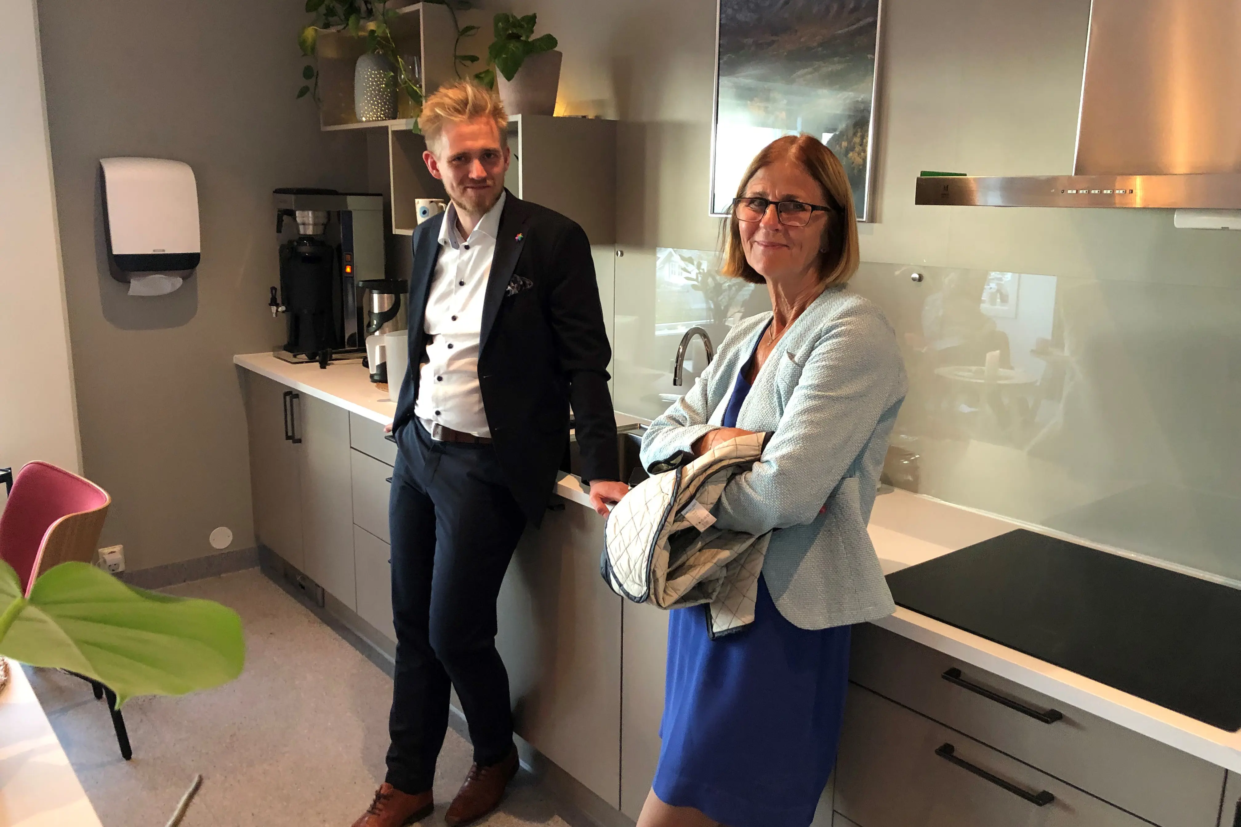 Mann og dame står på kjøkkenet og smiiler mot kamera