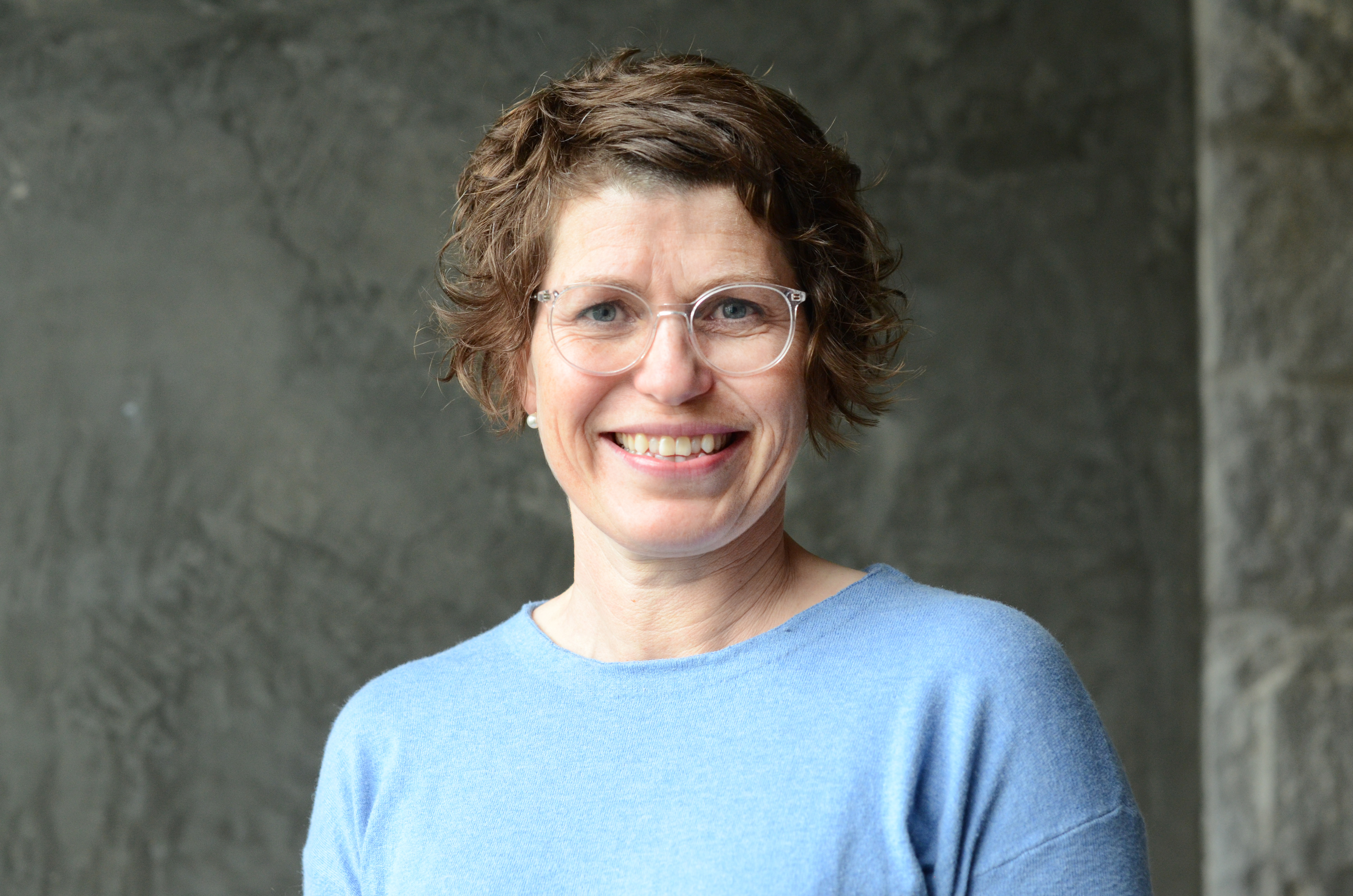 Dame med briller foran rød vegg