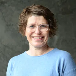 Dame med briller foran rød vegg