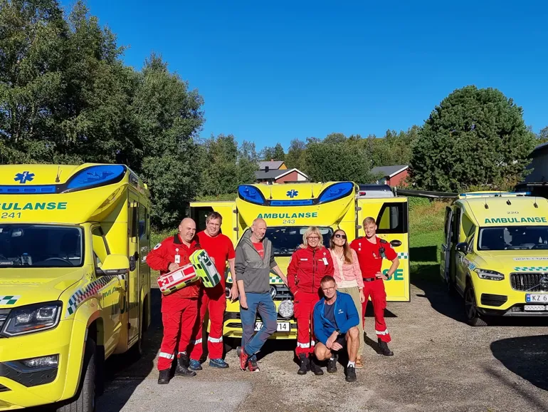 Gjeng med ambulansearbeidere smilende mot kamera