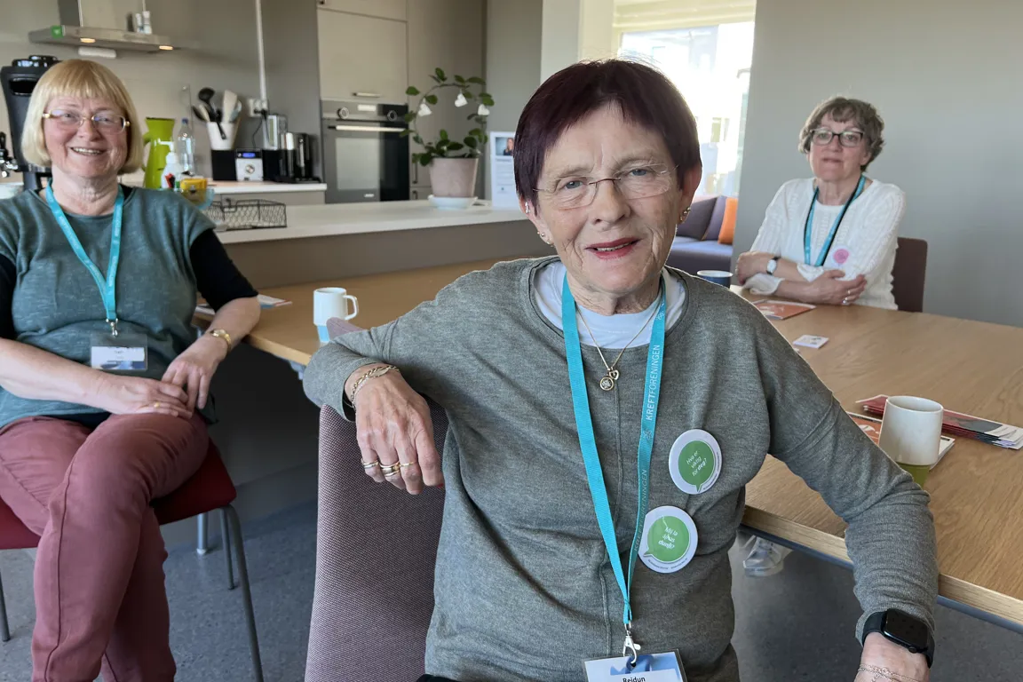 Tre damer som sitter og smiler mot kamera