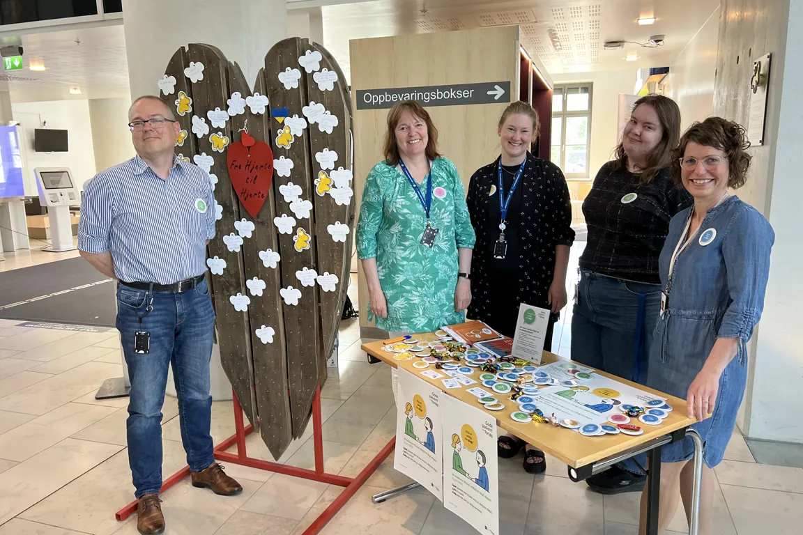 Fem personer som smiler mot kamera