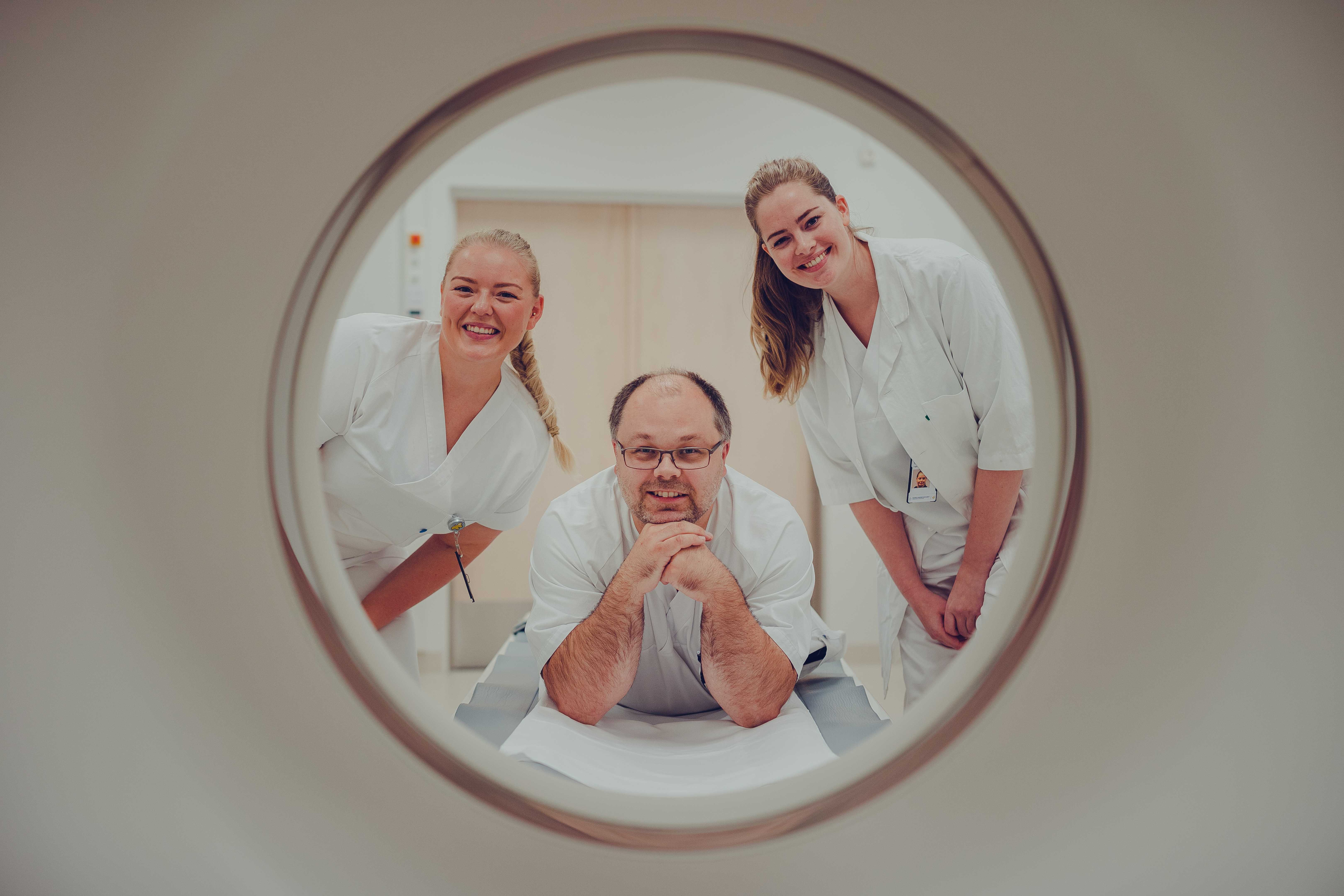 Tre radiologer som ser gjennom hullet til røntgenmaskinen