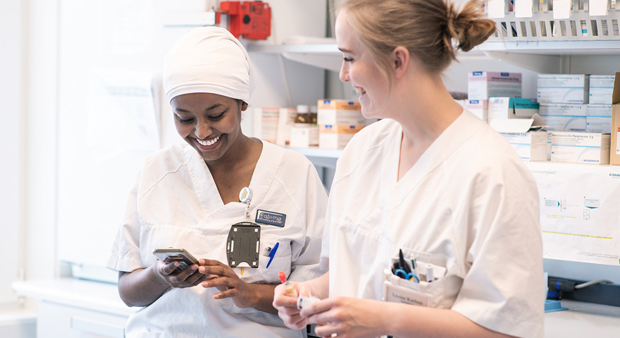 To damer som smiler og ser på mobil