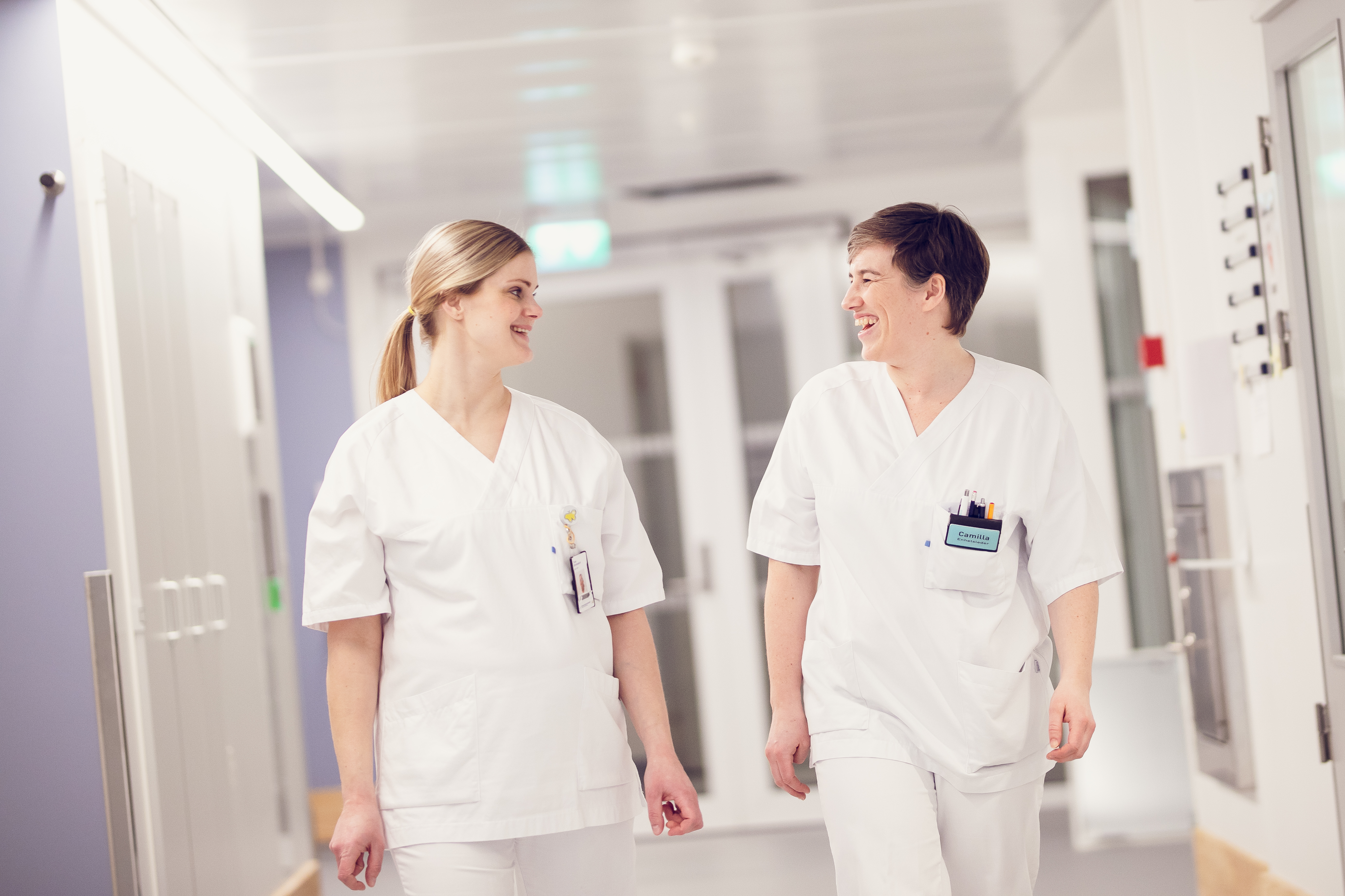 To sykepleiere som prater og går i en gang