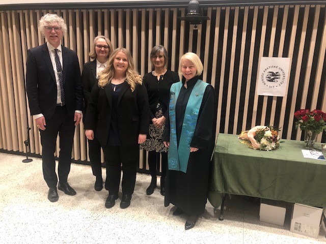 Fem personer står samlet og smiler