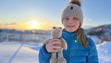 Jente som holder en bamse og smiler