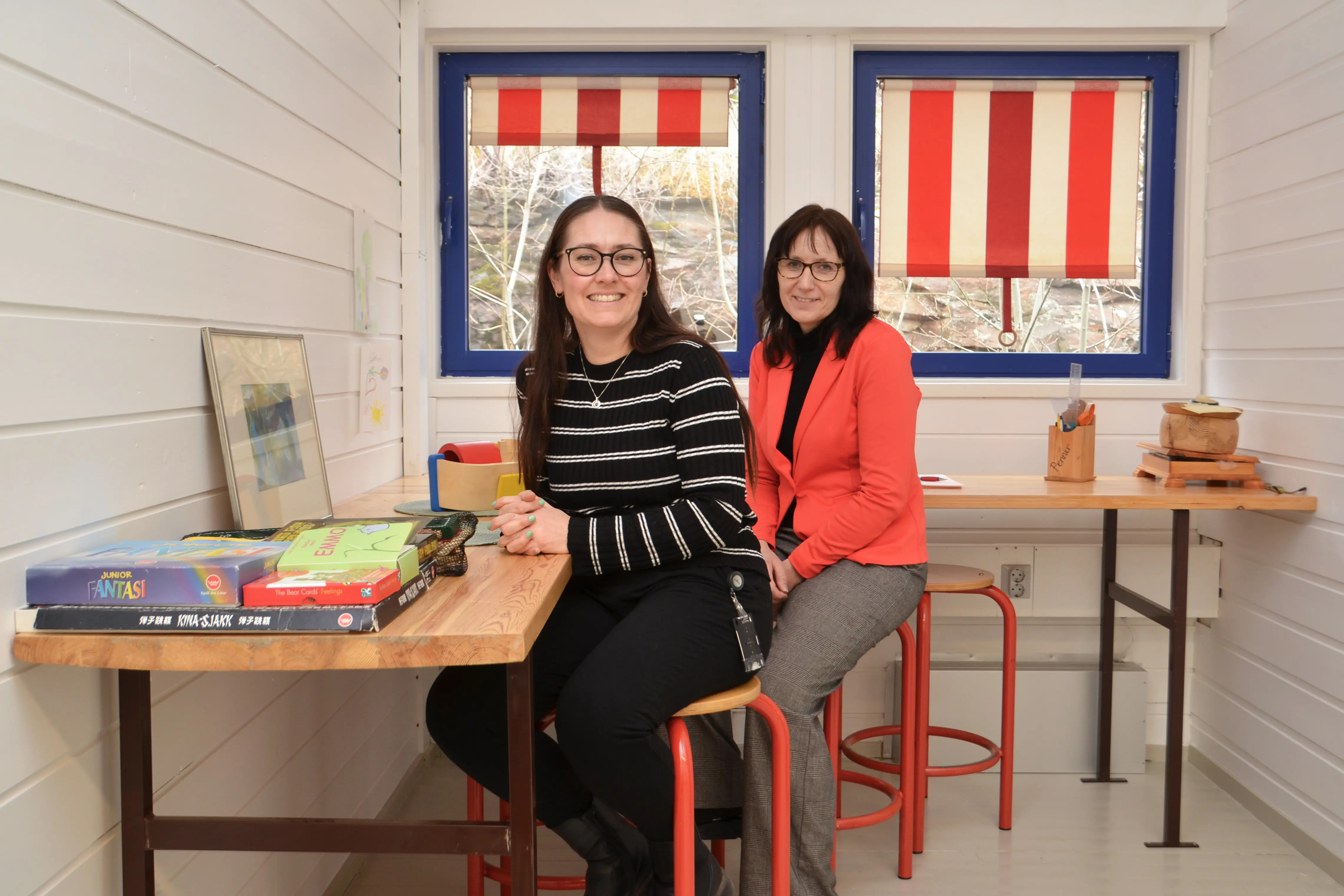 A couple of women sitting at a table with books and a flag