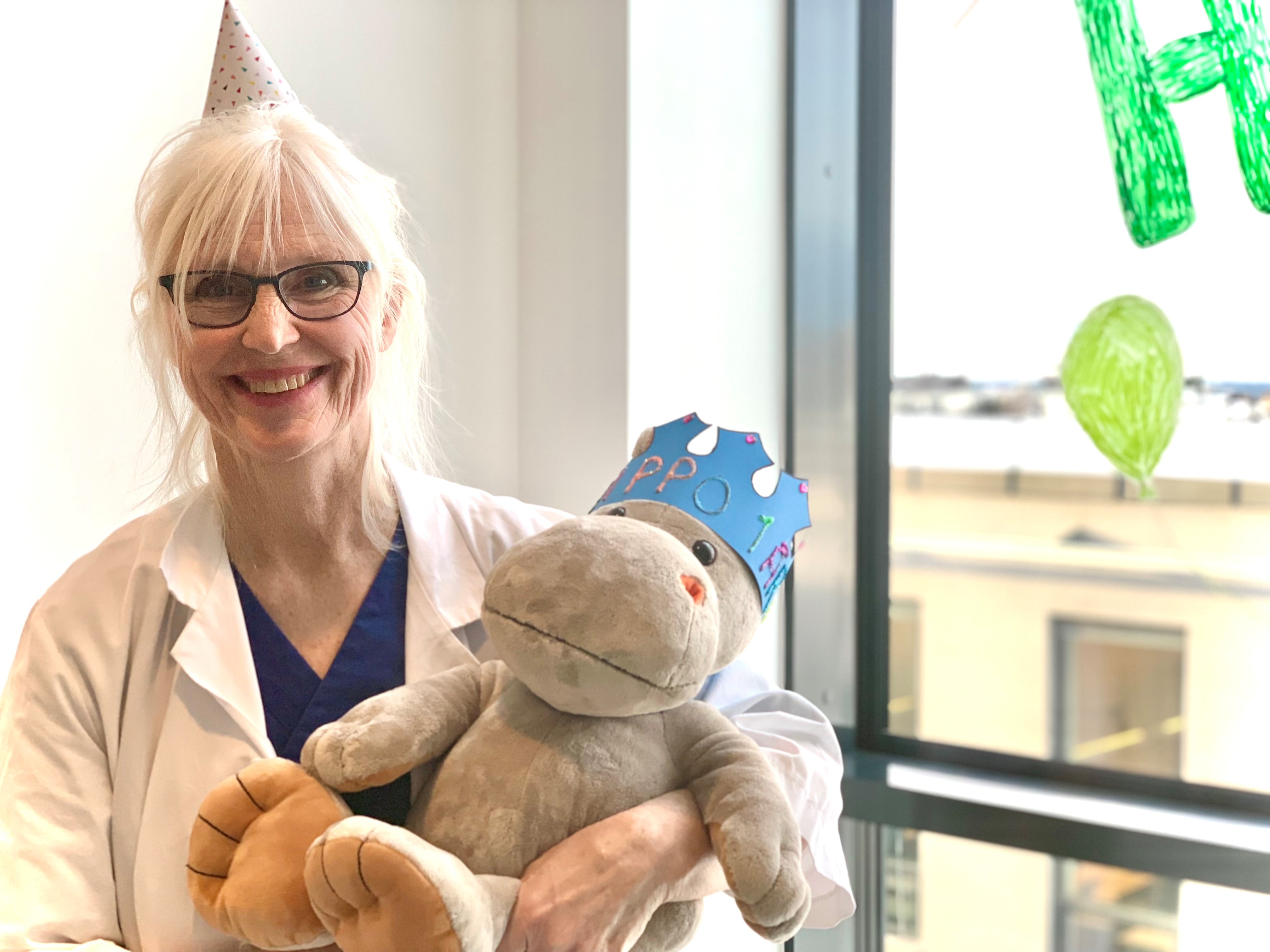 Dame som smiler mens hun holder bamse