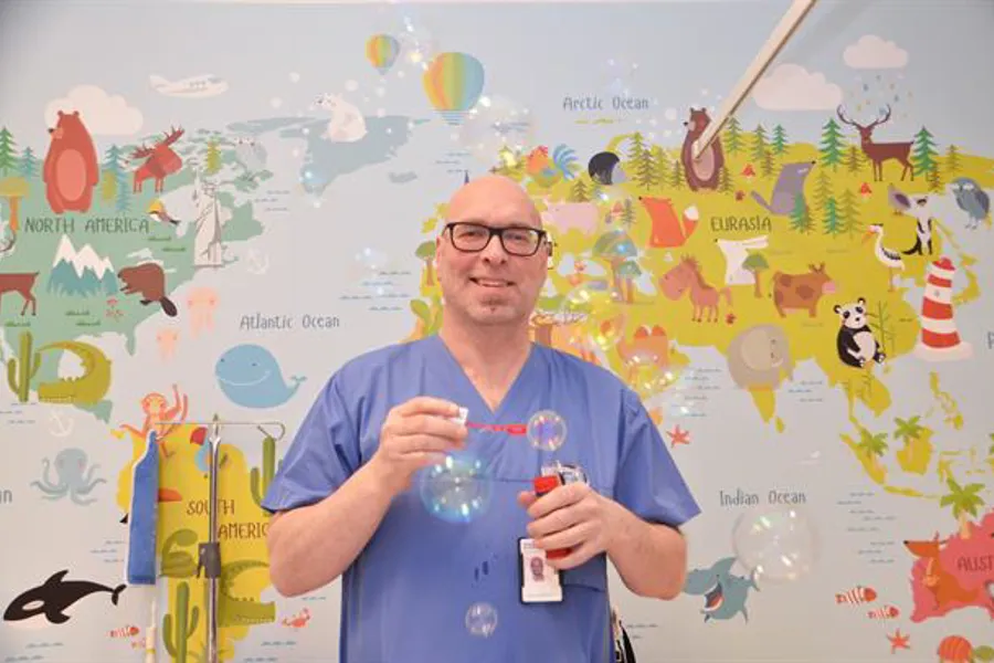 A man holding a drink and a stick in front of a map