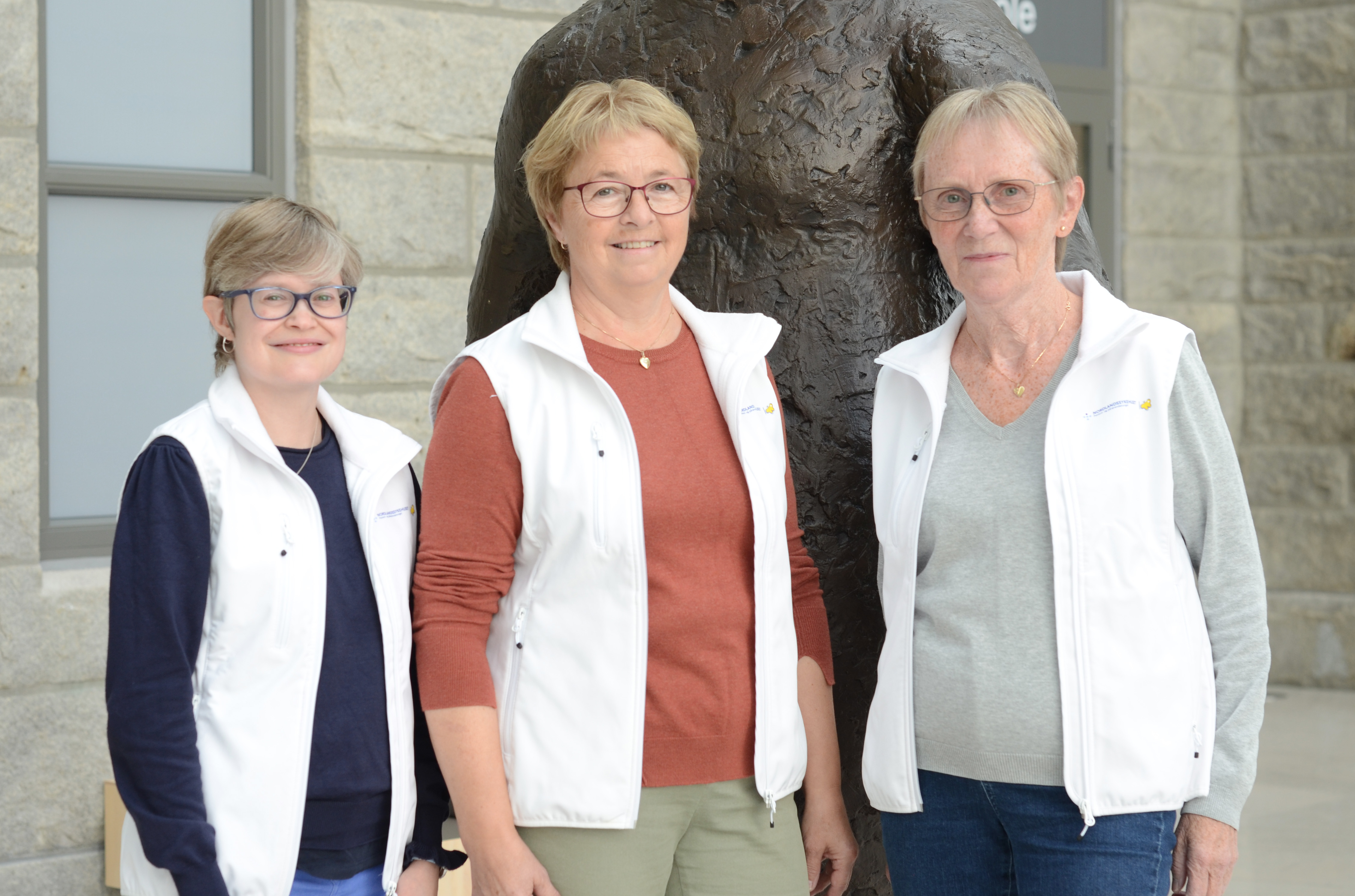 En gruppe kvinner som st&#229;r foran en statue