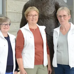 A group of women standing in front of a statue
