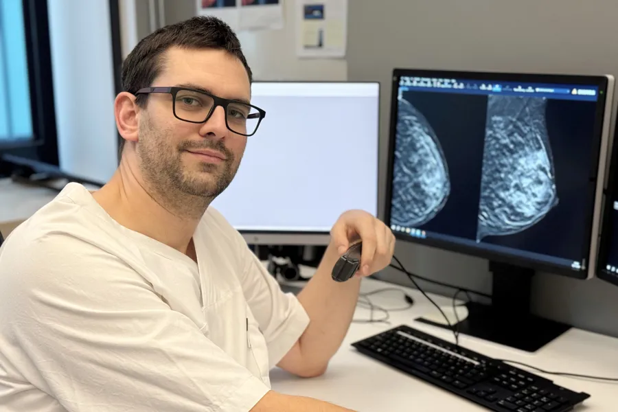 En mann som sitter ved et skrivebord med en datamaskin og et tastatur