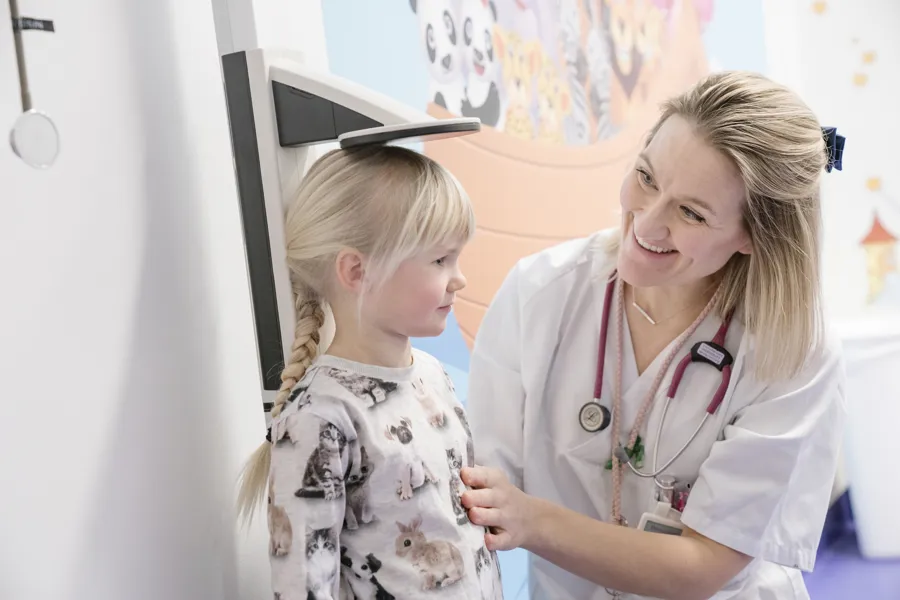 Lege som måler høyde på barn