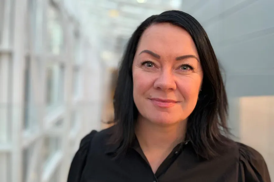En kvinne med mørkt hår som smiler
