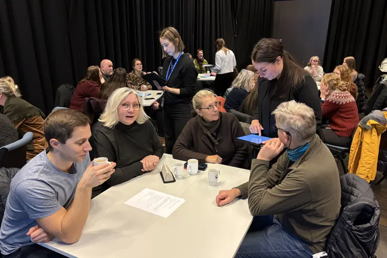 Gruppe mennesker som sitter samlet rundt et bord