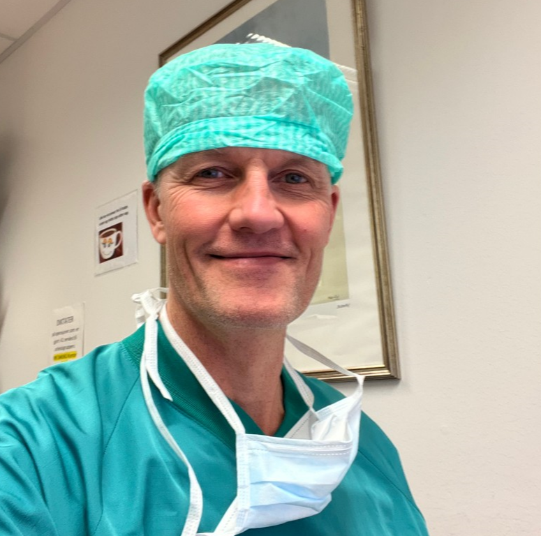 En mann med munnbind og grønne klær