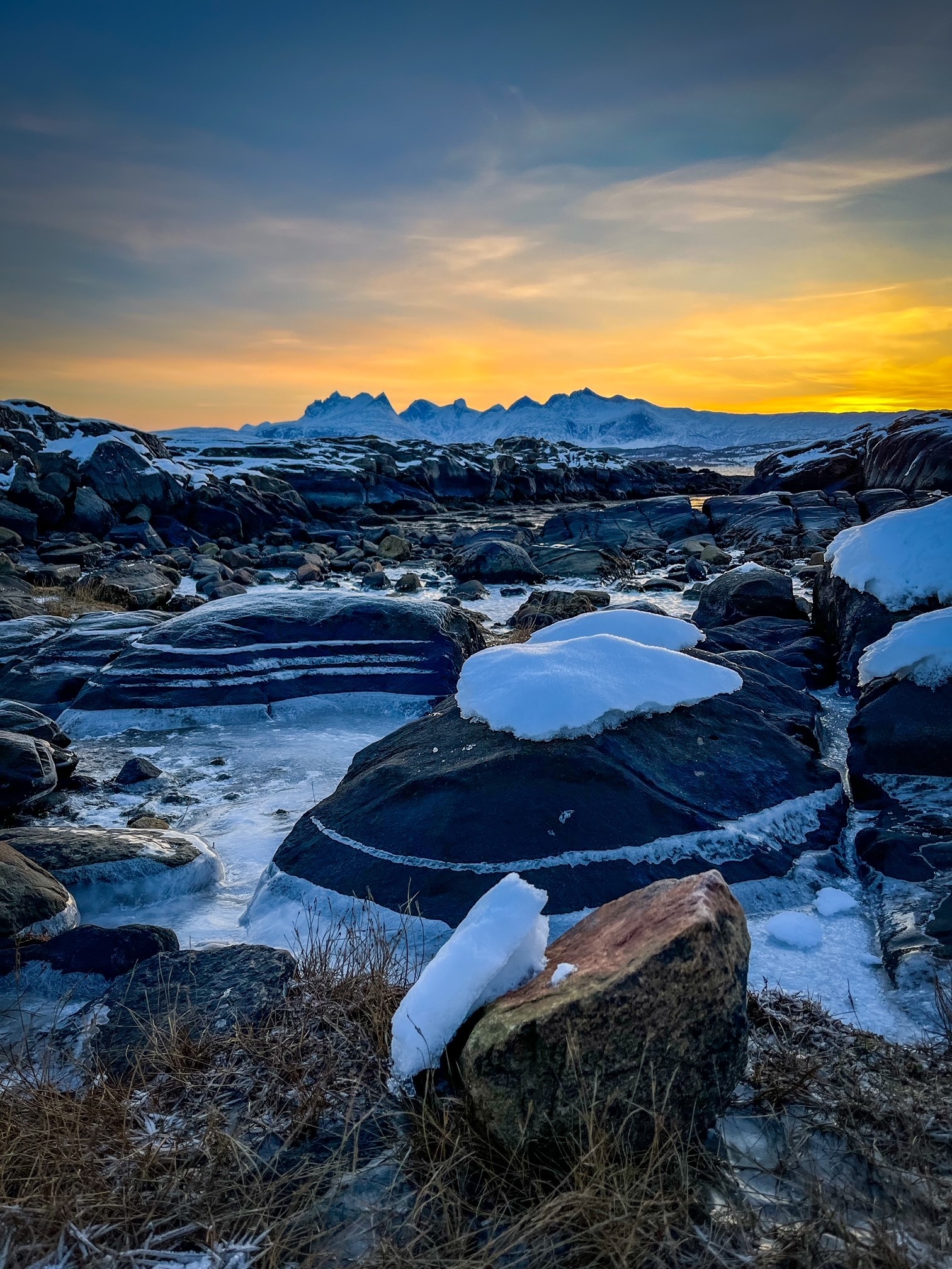 En steinete strand med snø