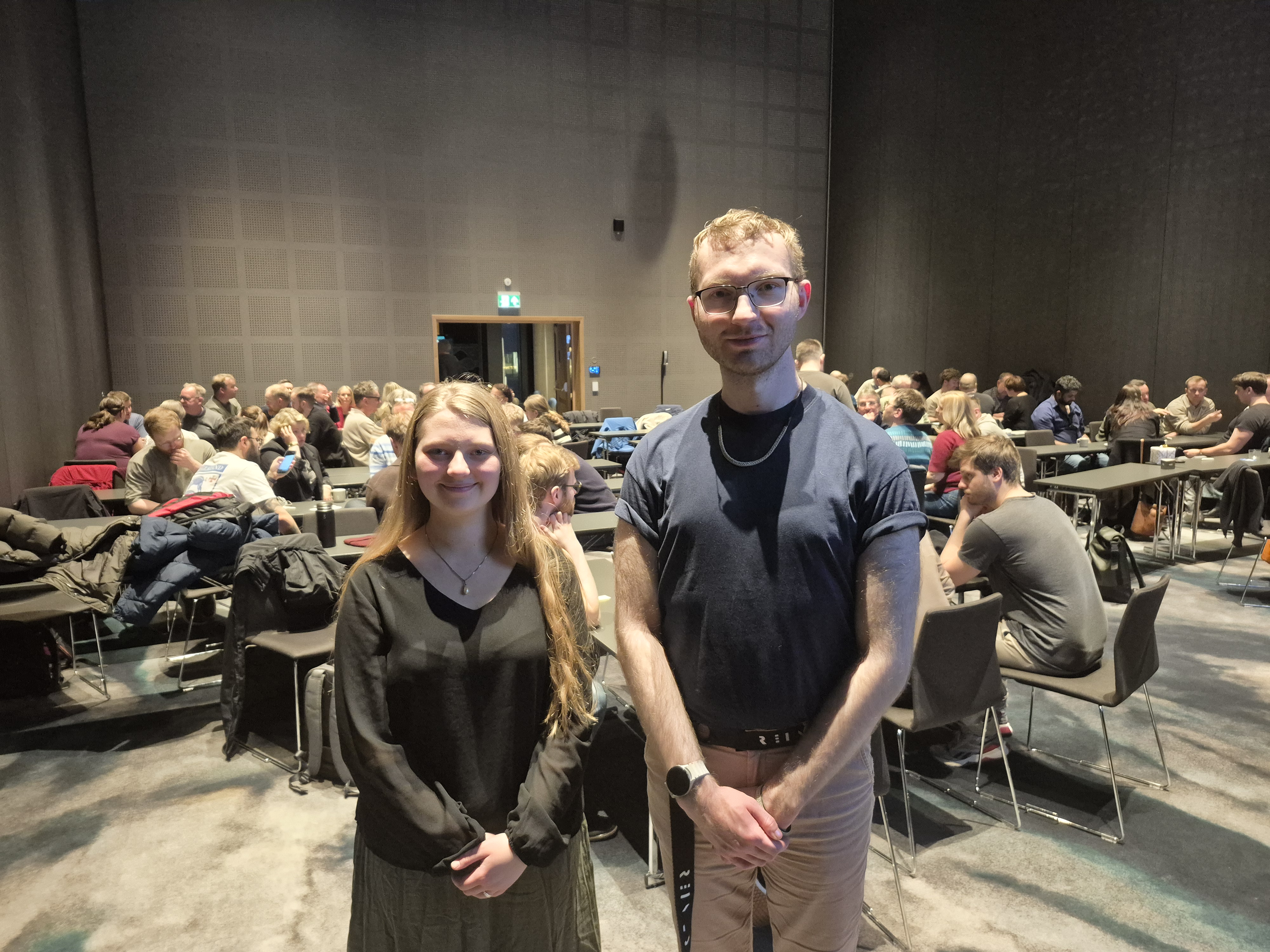 En mann og en kvinne poserer for et bilde foran et stort publikum