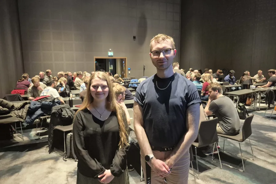 En mann og en kvinne poserer for et bilde foran et stort publikum