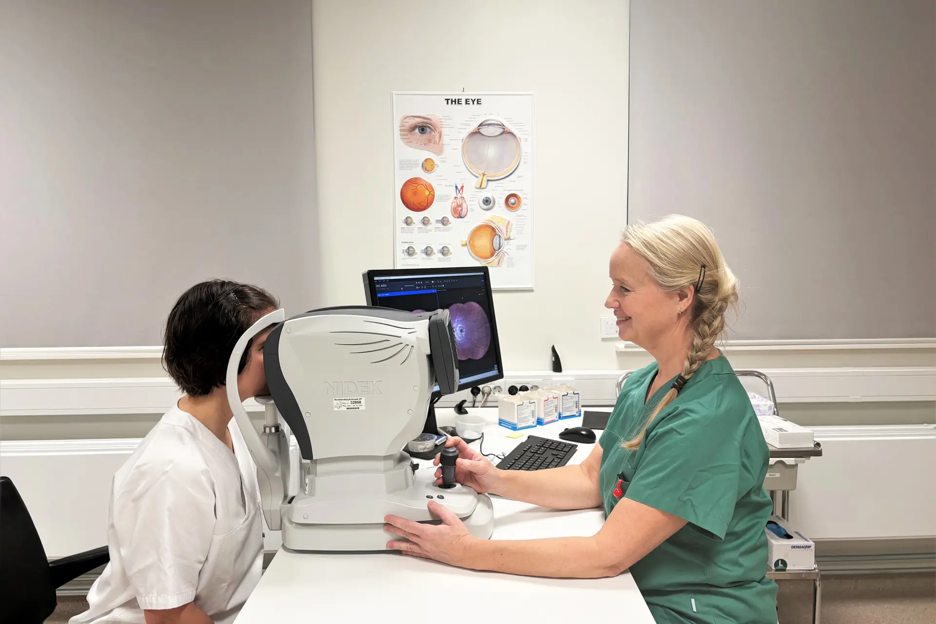 En lege som viser en pasient noe på datamaskinen