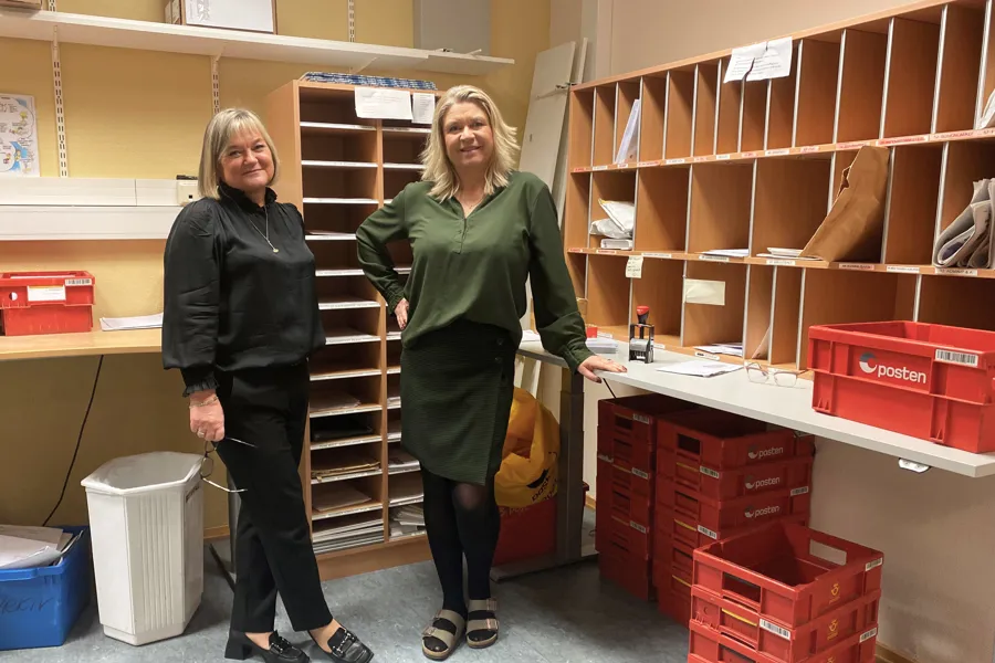 Et par kvinner som står i et rom med hyller av bøker