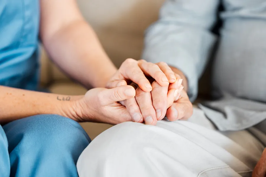 Sykepleier holder pasientens hånd