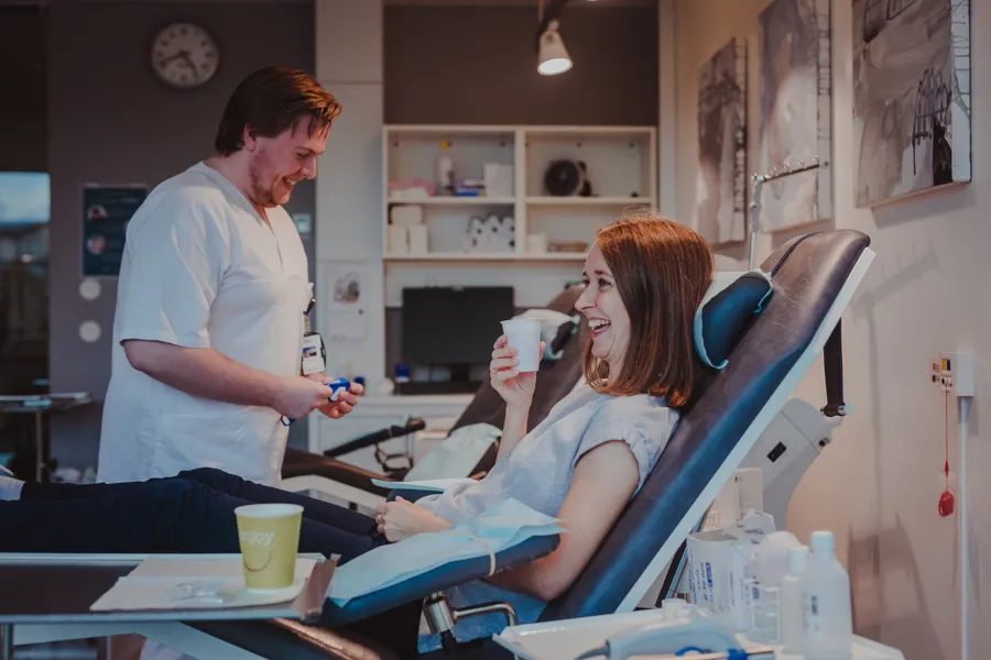 Dame som sitter i en blodgiverstol og drikker saft