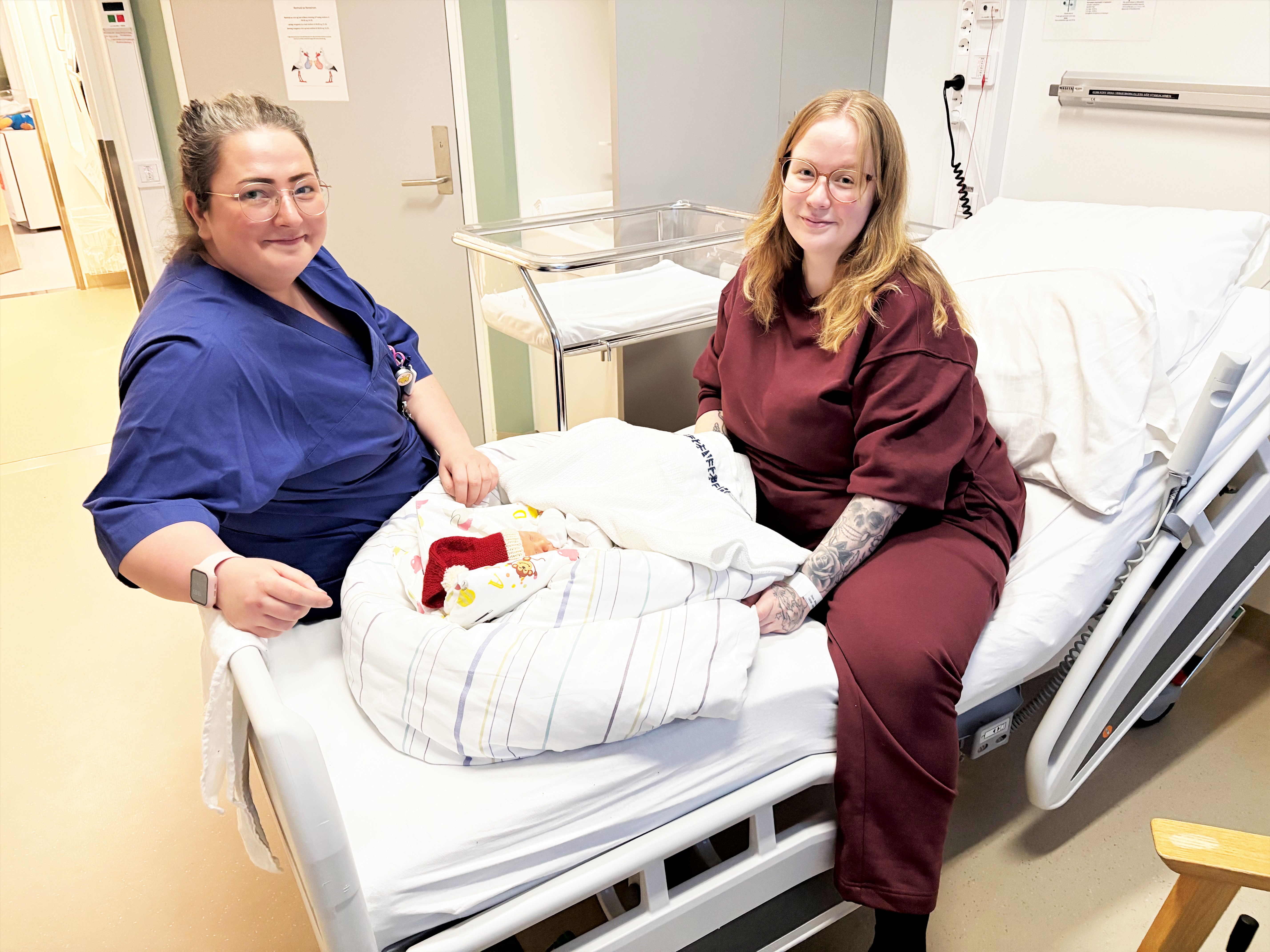 to damer som sitter i en seng med en baby