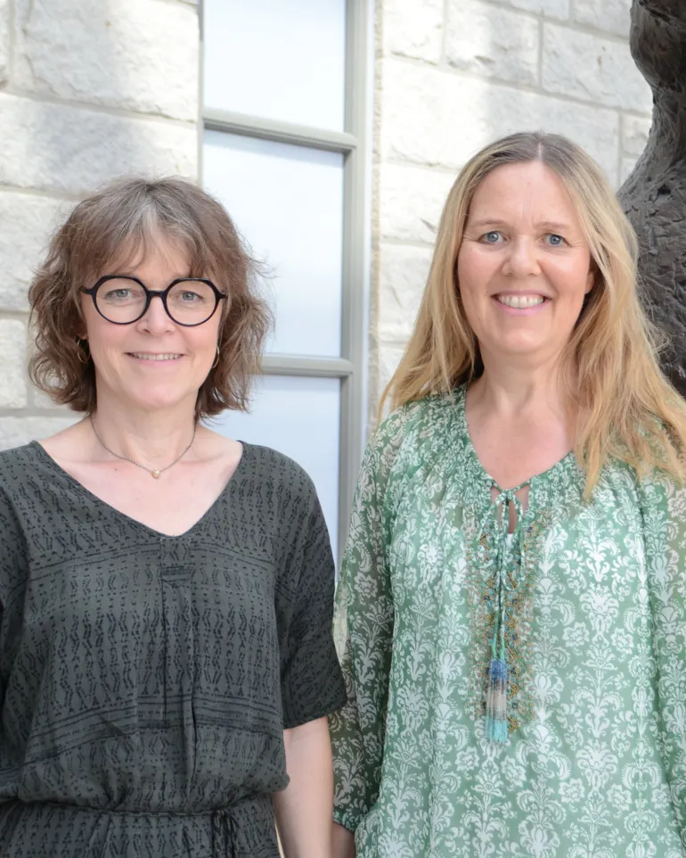 To kvinner som står ved siden av en statue